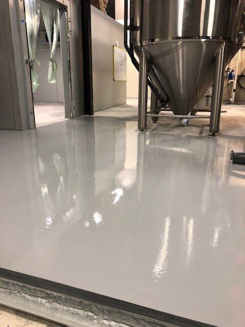A row of stainless steel tanks are lined up in a brewery.