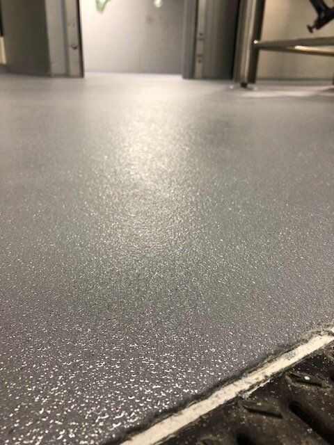 A close up of a gray floor next to a drain.