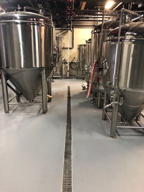 A row of stainless steel tanks are lined up in a factory.
