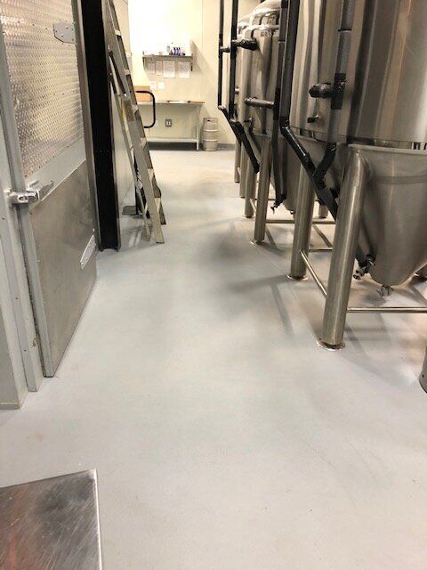 A room with a lot of stainless steel tanks on the floor.