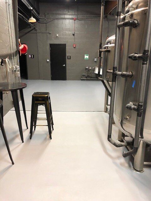 A truck is parked in a brewery next to a fence.