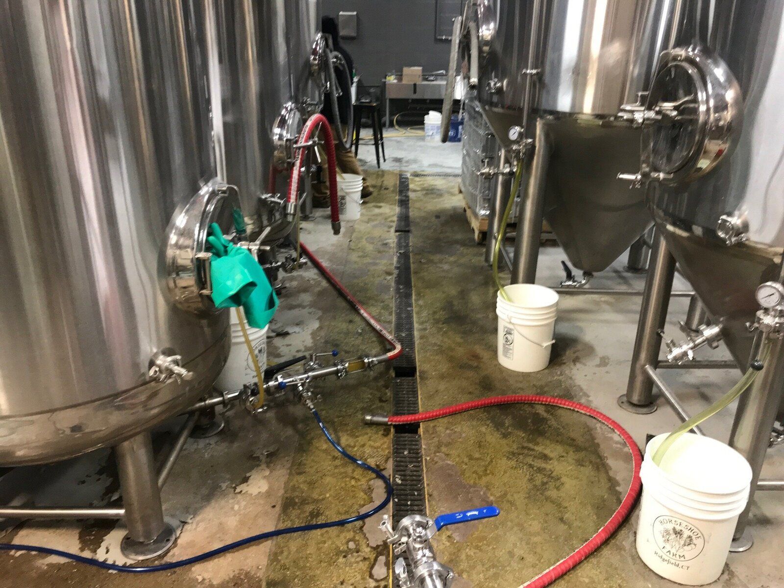 A brewery with a lot of stainless steel tanks and buckets.