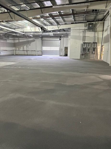 A large empty warehouse with a concrete floor and a garage door.