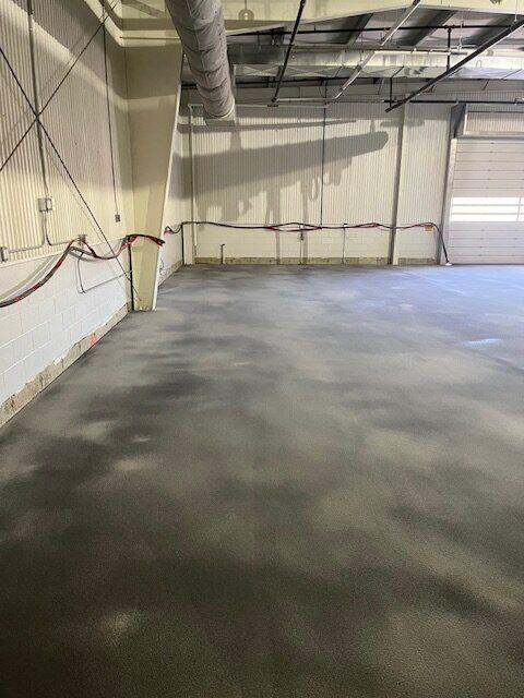 A large empty warehouse with a concrete floor and a garage door.