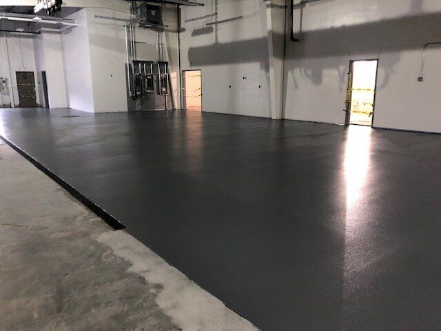 A large empty room with a gray floor and white walls.