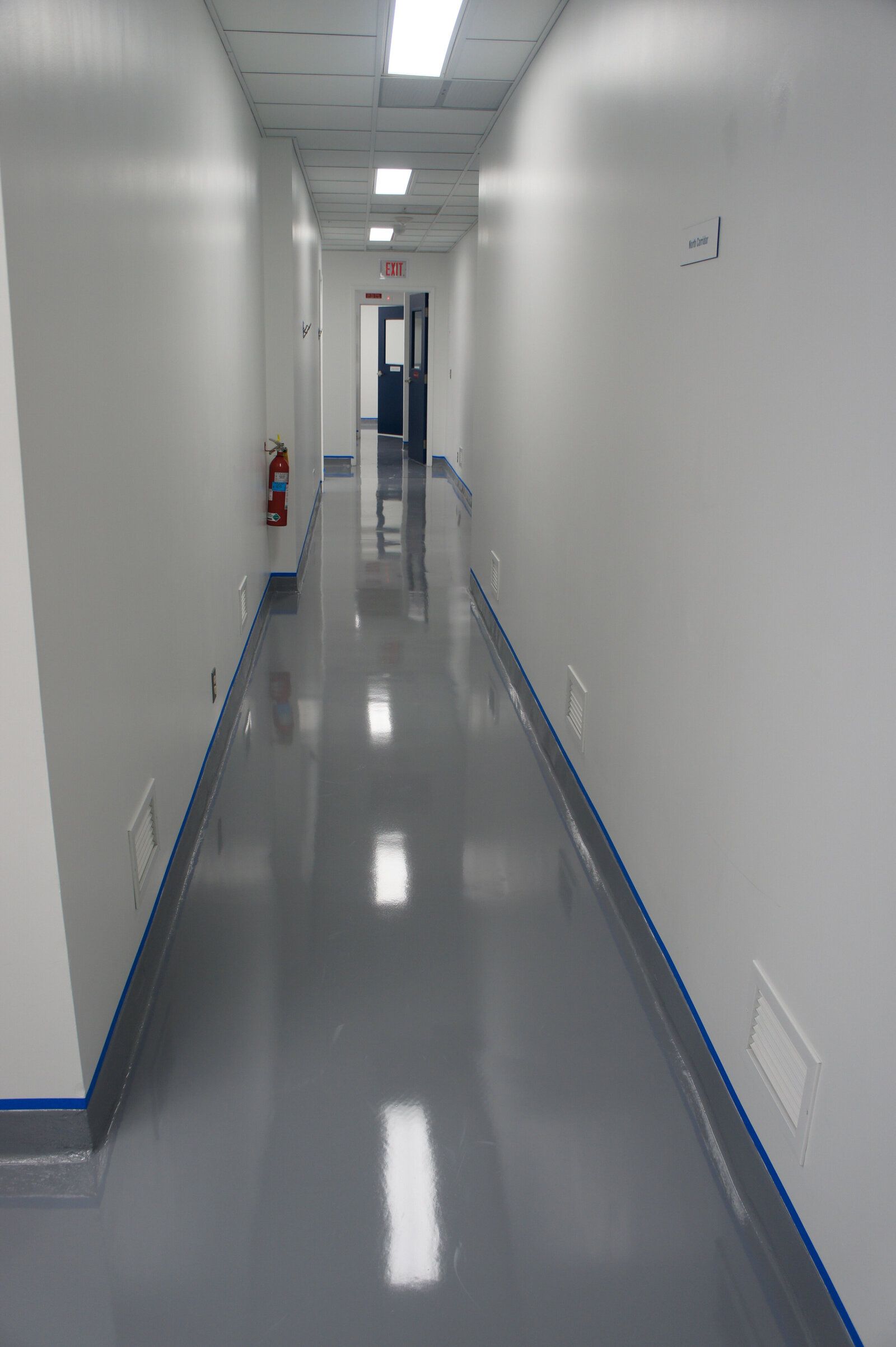 A long hallway with a gray floor and white walls in a building.
