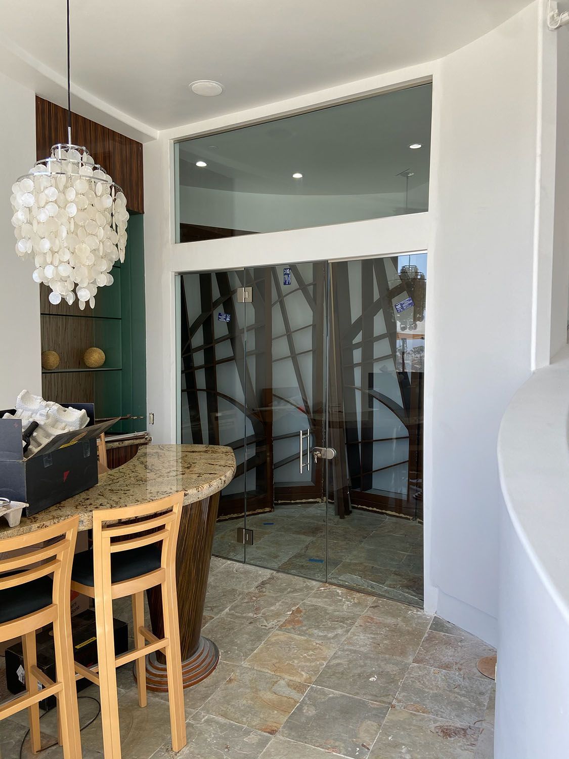 Bar with stools, glass door with abstract art, decorative light fixture.