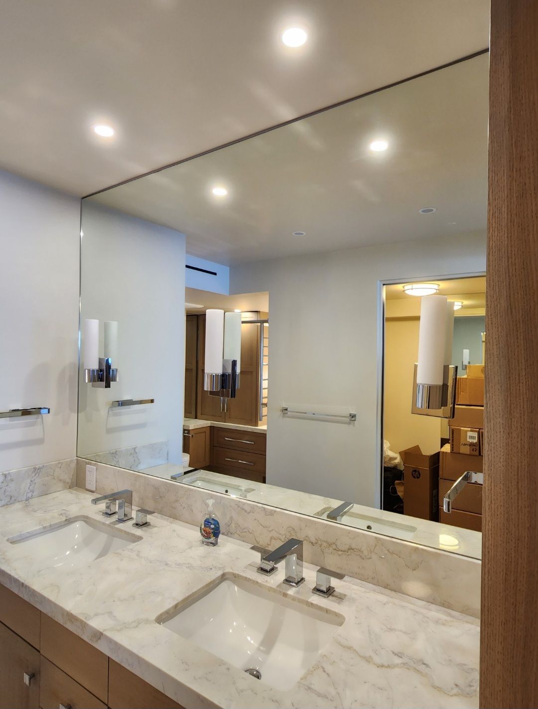 Bathroom with large mirror over double vanity with marble countertop and chrome fixtures.