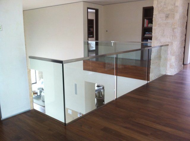 Interior view of a modern home with glass railing on an upper level overlooking a lower floor.