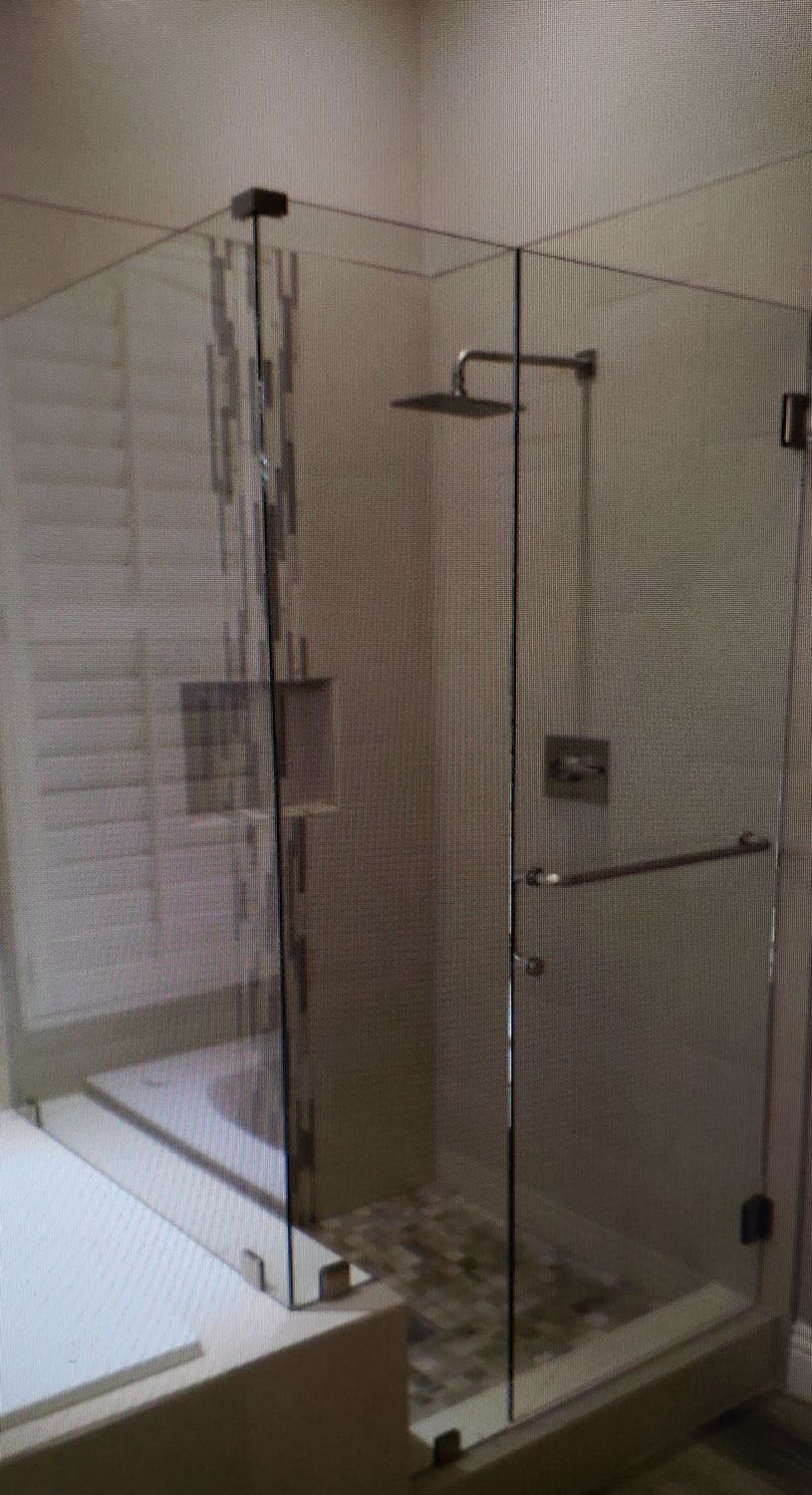 Glass-walled shower in a bathroom with showerhead, handle, and pebble floor.
