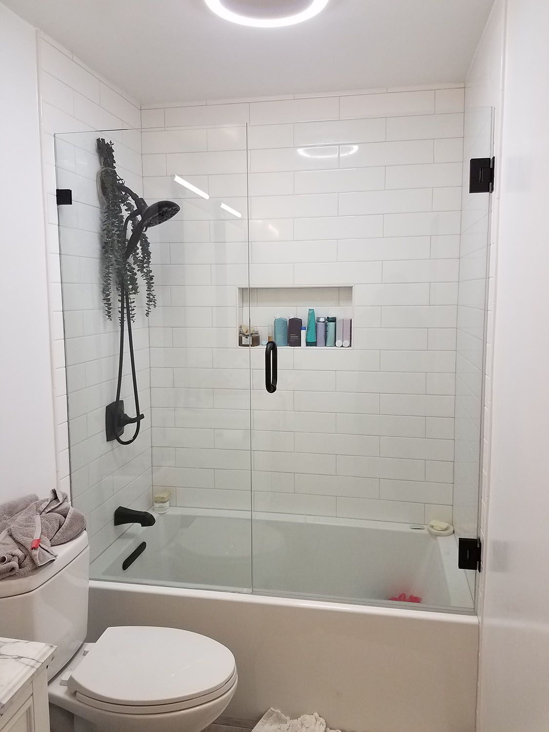 Bathroom with white subway tile, a glass shower door, and a toilet.
