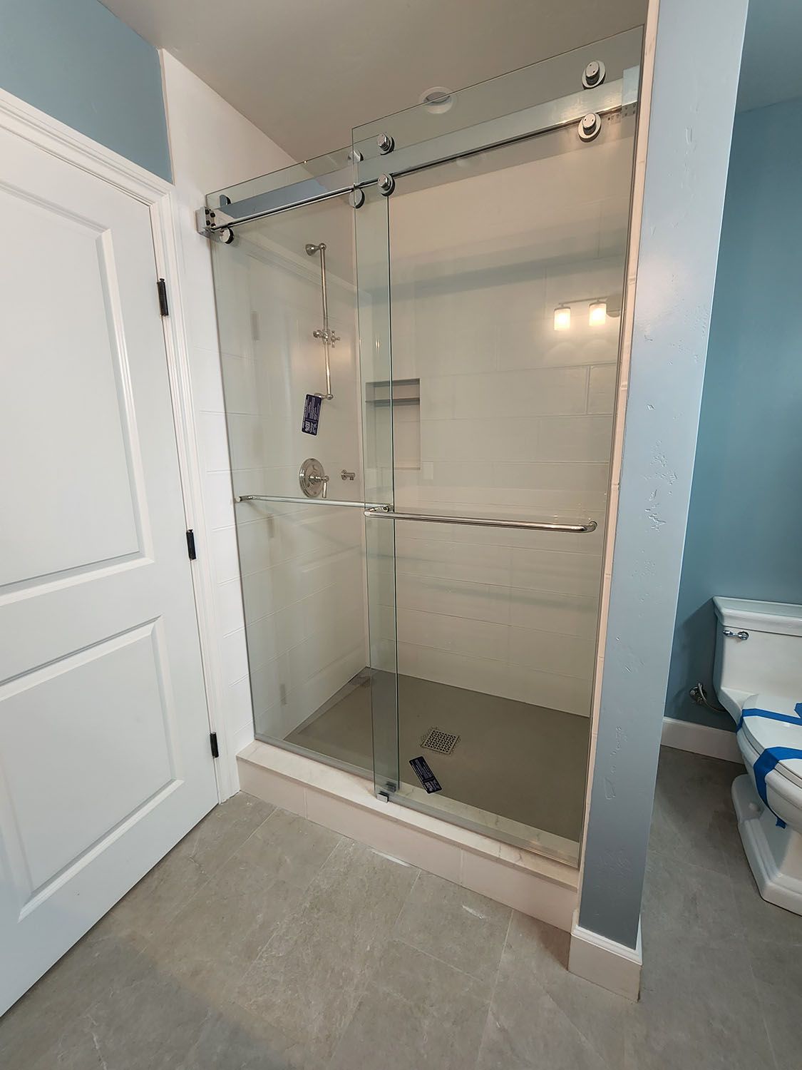Glass shower enclosure with sliding door in a bathroom.