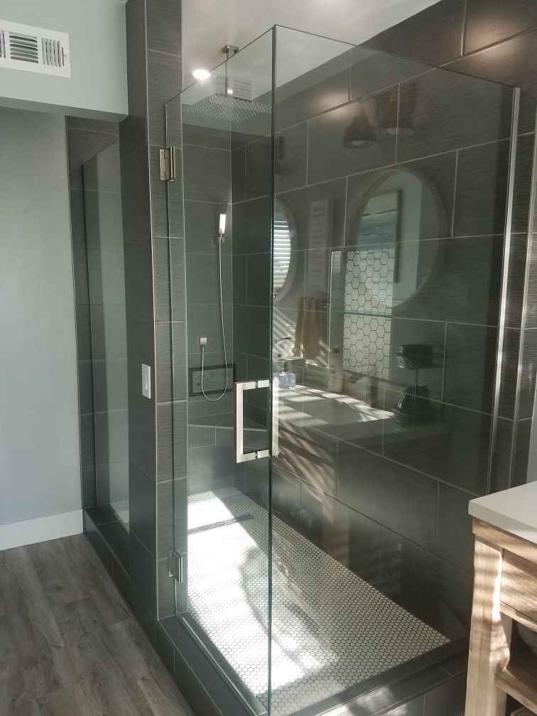 Modern glass shower with gray tiled walls and a white tile bench.