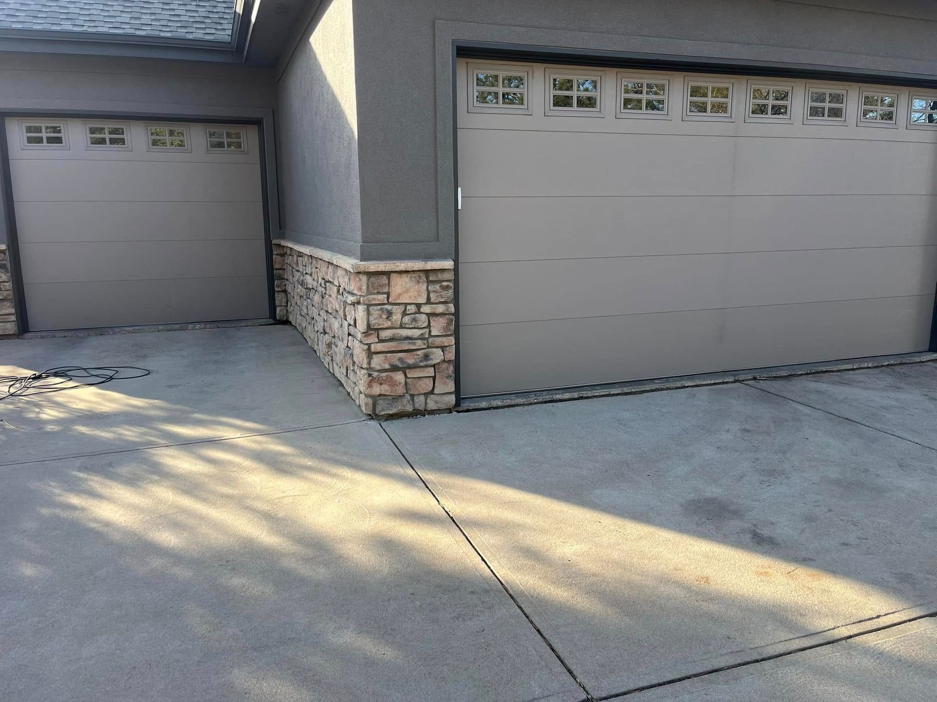 There are two garage doors on the side of a house.