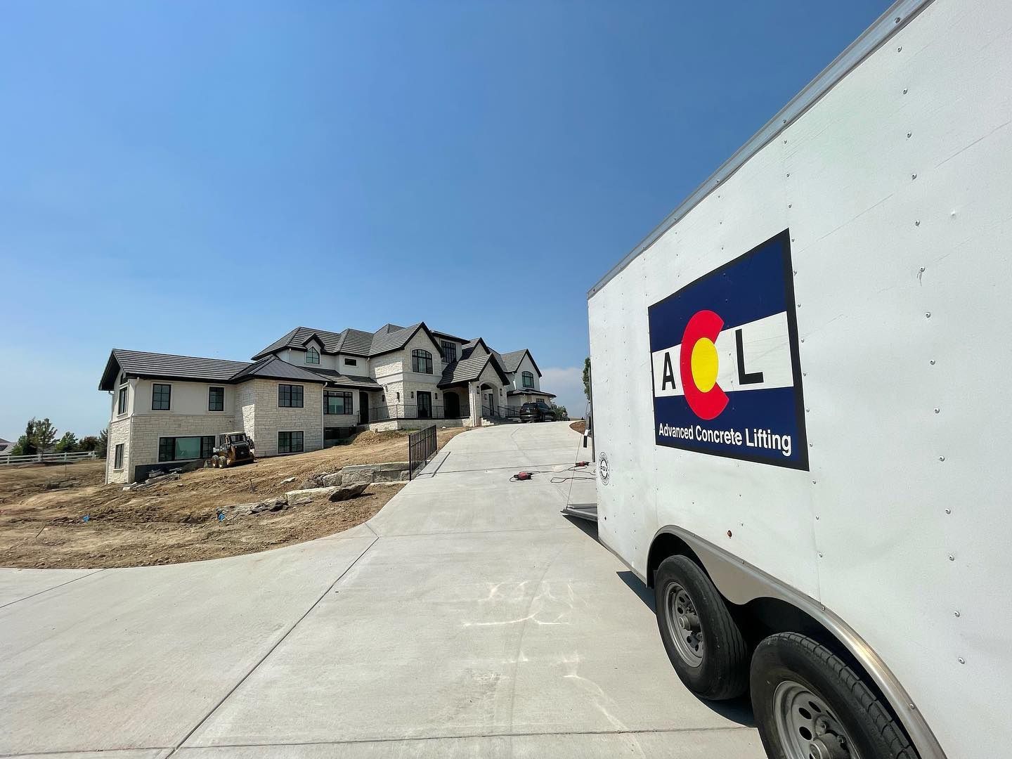 A white trailer is parked in front of a house under construction.