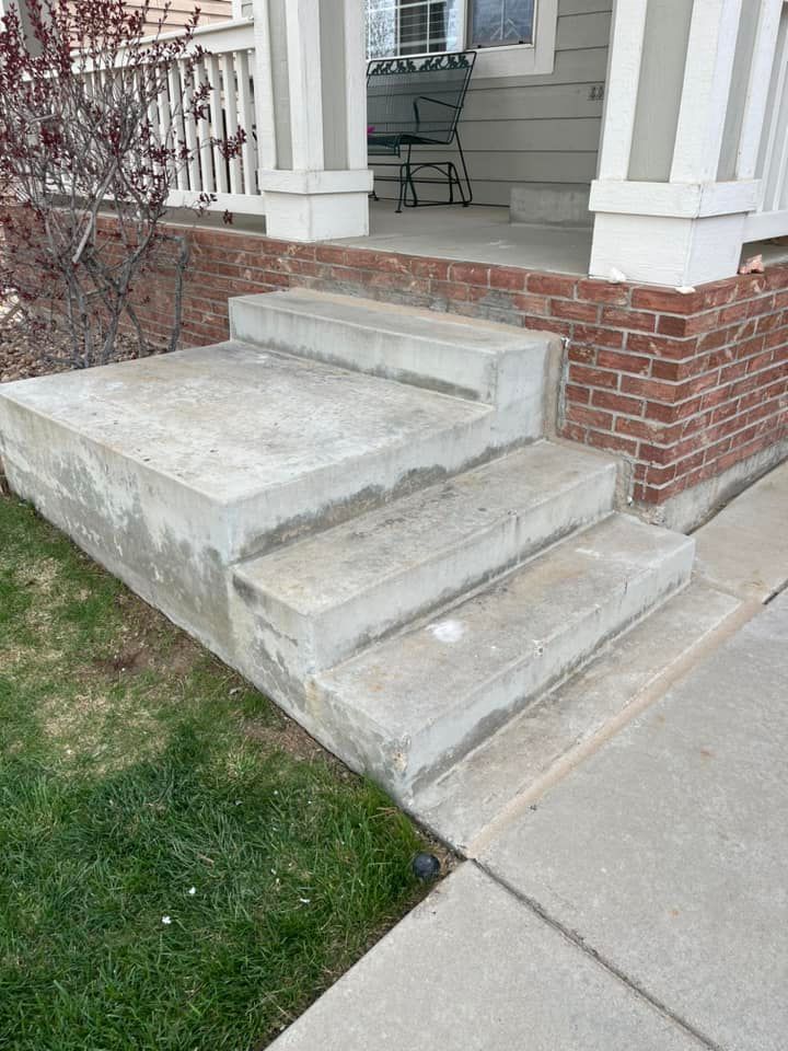 A set of concrete steps leading up to a porch of a house.