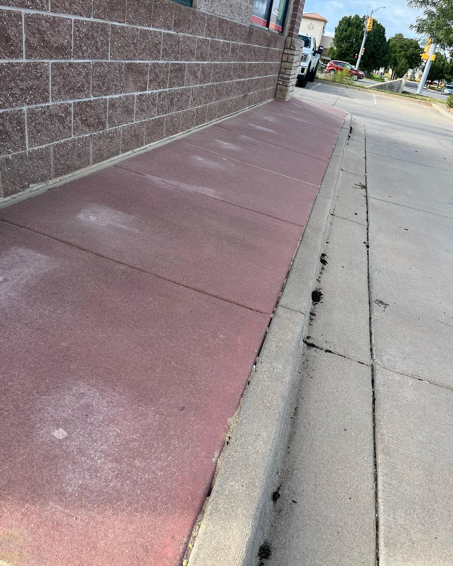 A sidewalk with a curb and a brick wall in the background.