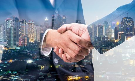 Partnership image of two people shaking hands with the city behind them.