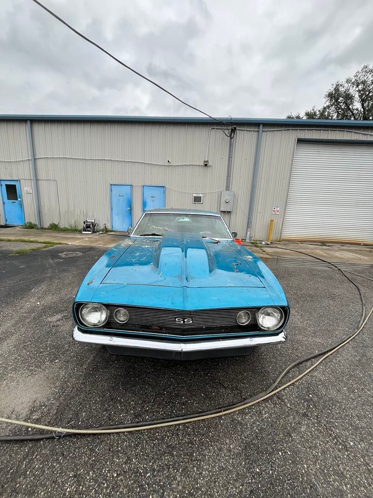 A blue car is parked in front of a building.