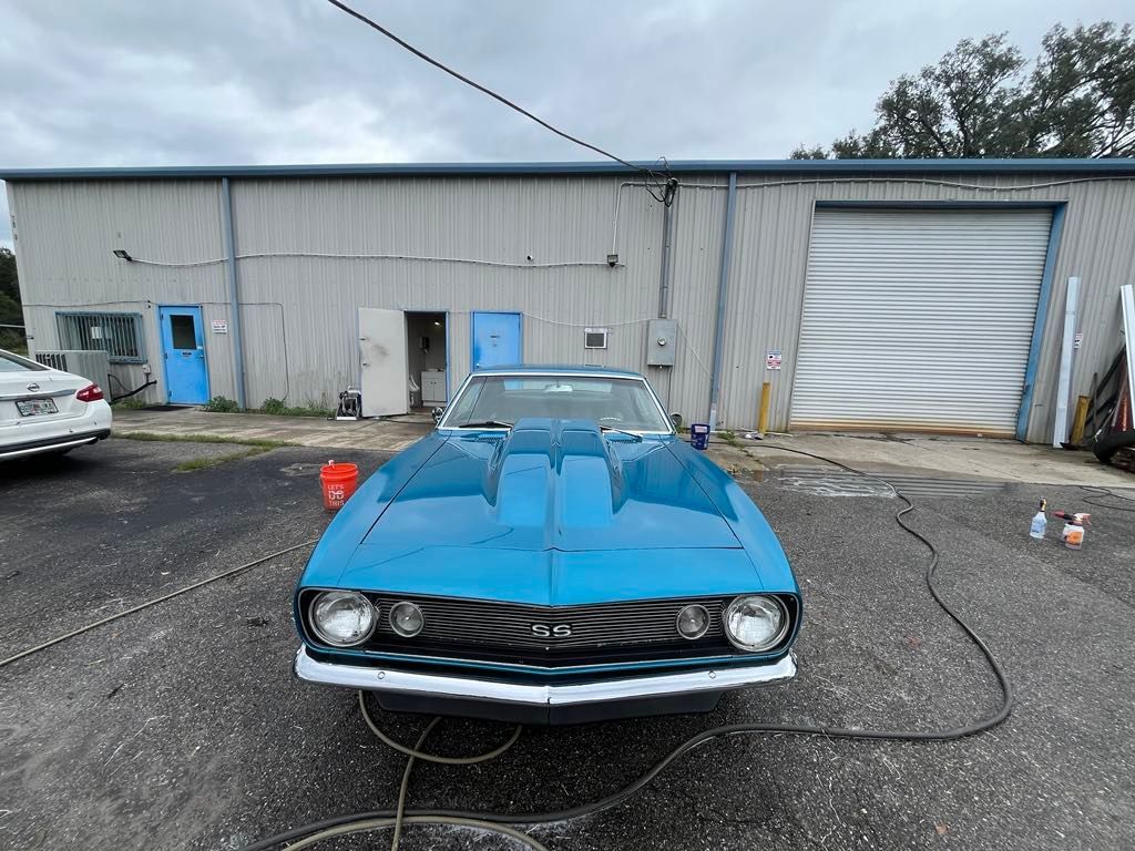 A blue car is parked in front of a garage.