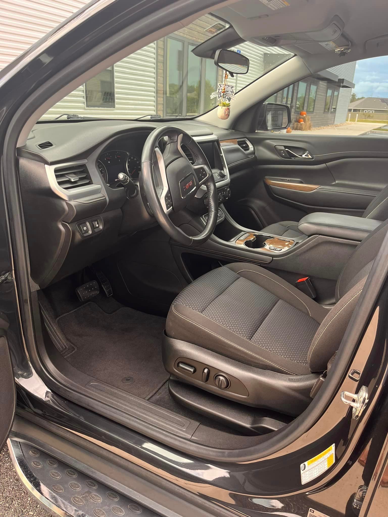 The interior of a black car with the door open.