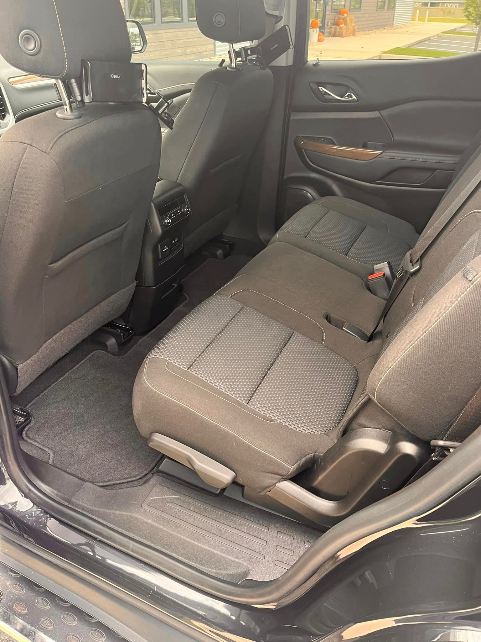 The back seat of a black suv with the door open.