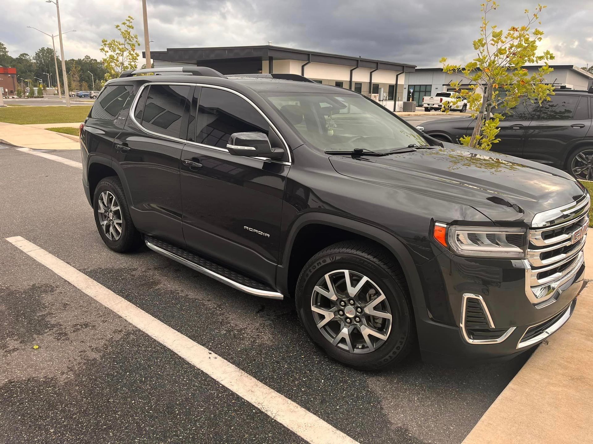 A black gmc acadia is parked in a parking lot.