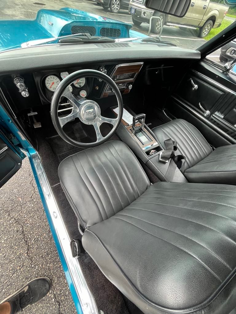 The interior of a blue car with black seats and a steering wheel.