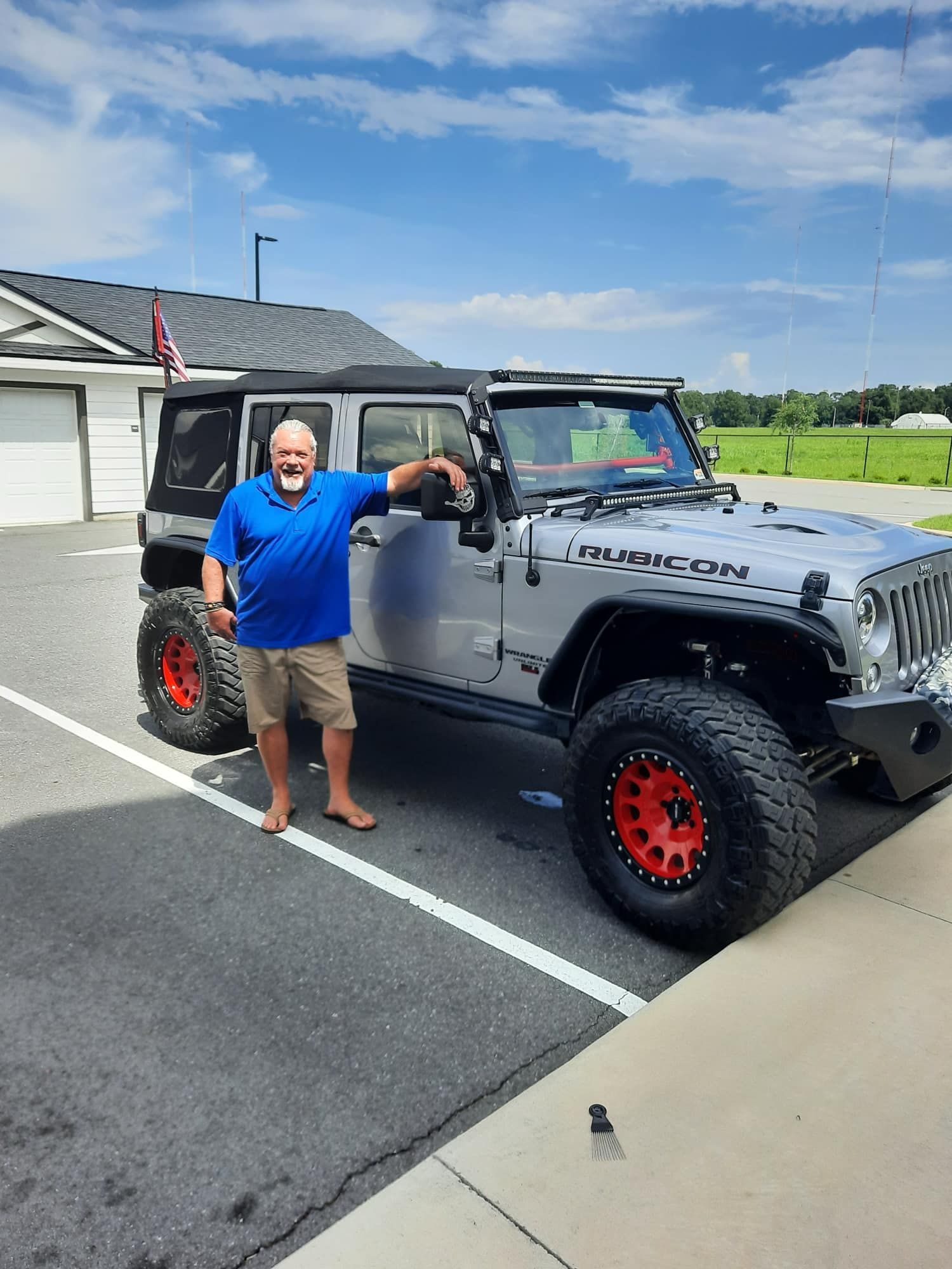 A man is standing next to a jeep in a parking lot.