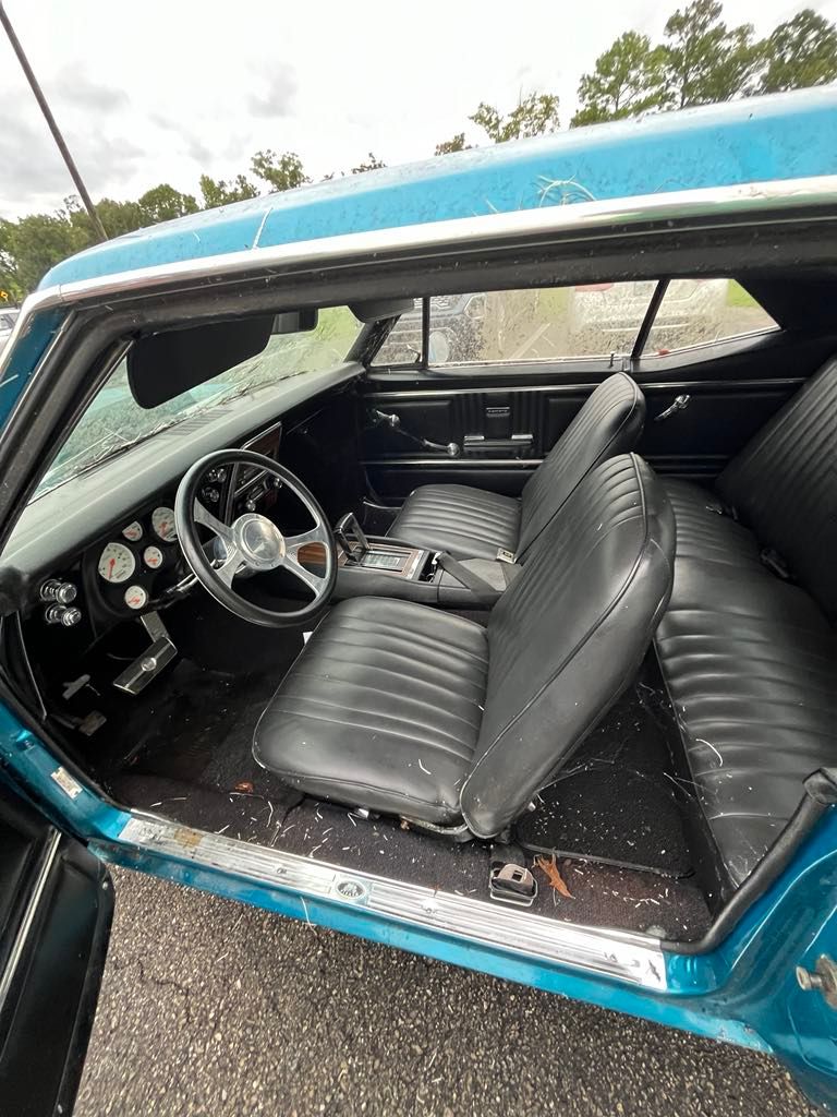 The interior of a blue car with black seats and a steering wheel.