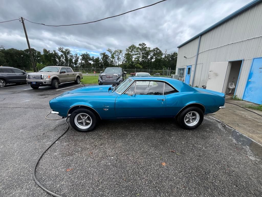 A blue car is parked in a parking lot next to a building.