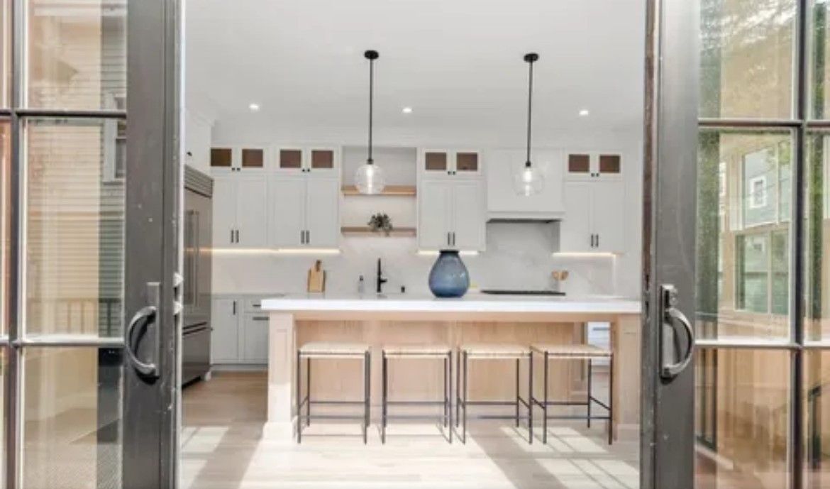 A kitchen with a large island and stools is visible through the sliding glass doors.