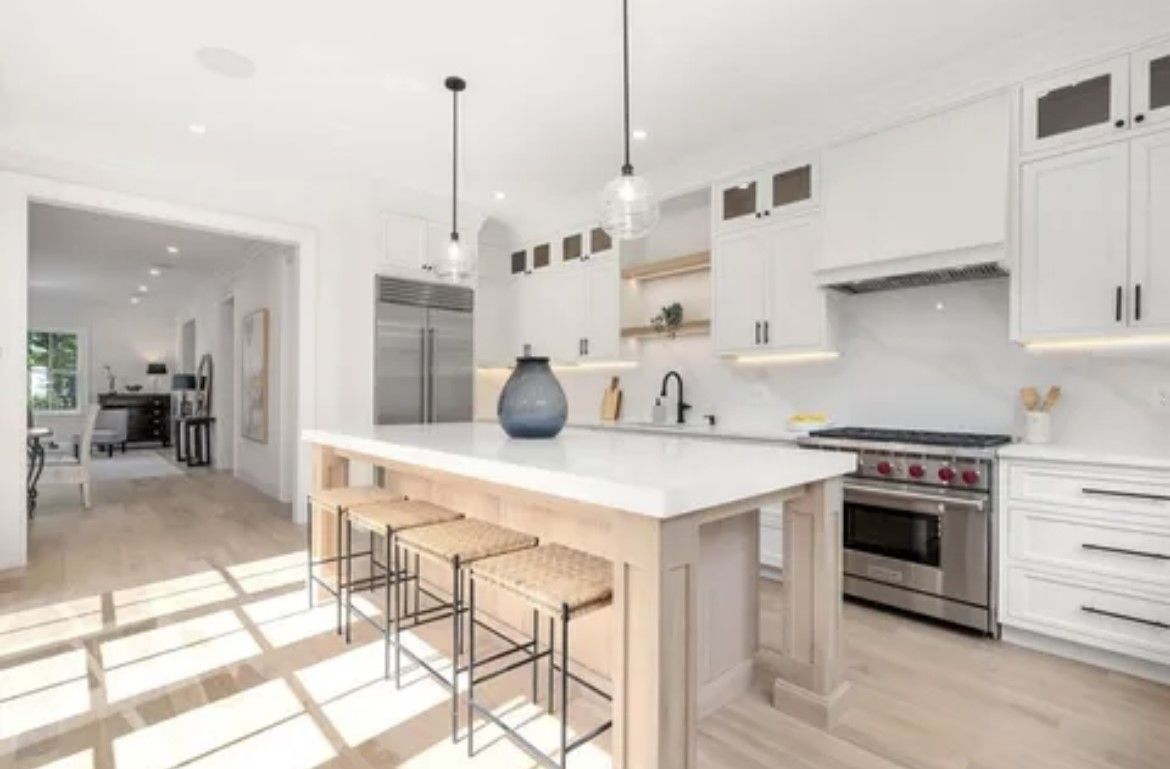A kitchen with white cabinets, stainless steel appliances, and a large island.