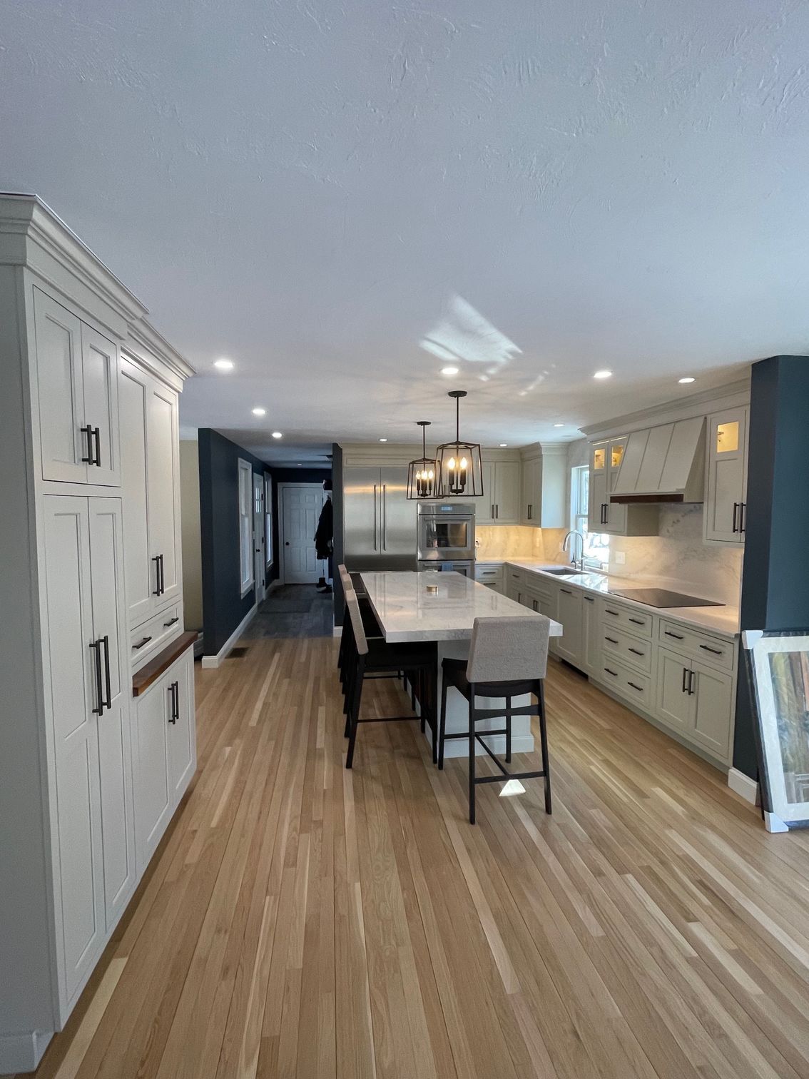 Modern kitchen with light wood floors, white cabinets, and a large island with seating.
