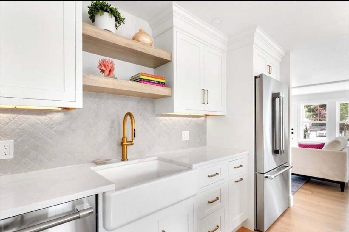 A kitchen with white cabinets, stainless steel appliances, a sink and a refrigerator.