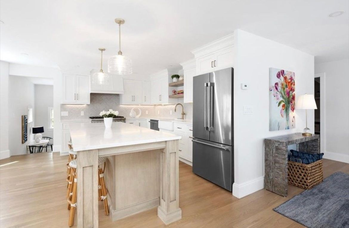A kitchen with a large island and a stainless steel refrigerator.