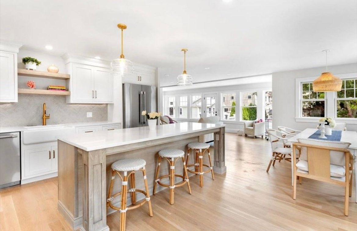 A kitchen with a large island, stools and a table.