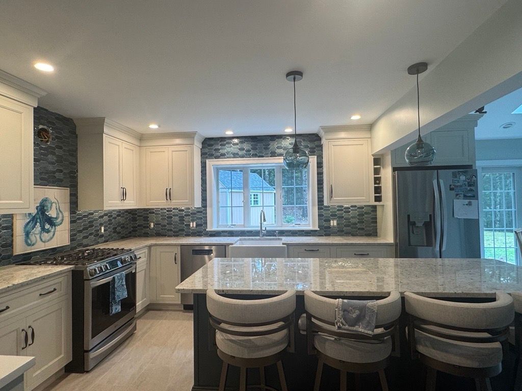 A kitchen with white cabinets, stainless steel appliances, and a large marble table