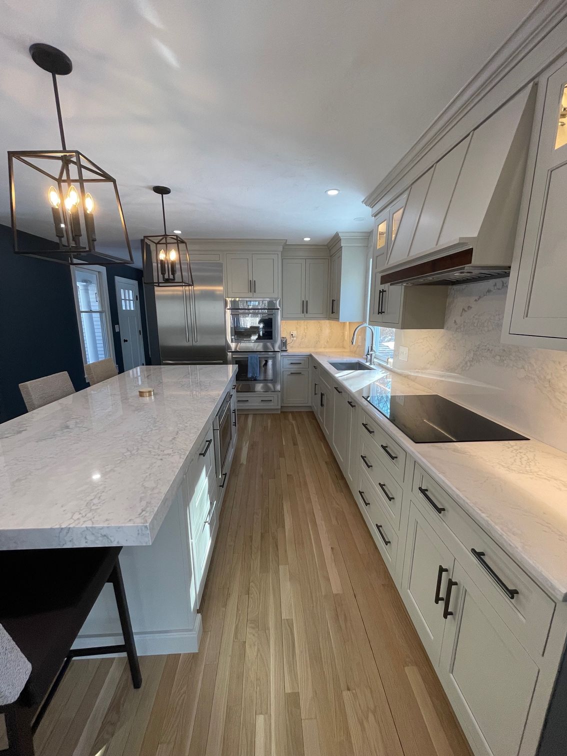 Modern kitchen with light wood floor, white cabinets, and stainless steel appliances.