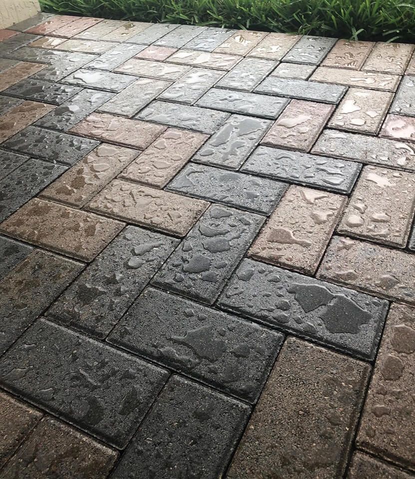 A close up of a brick walkway with water drops on it.