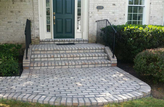 Brick walkway and steps leading to a green front door of a house