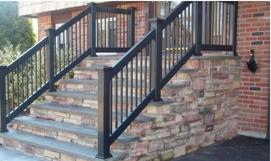 Stone outdoor staircase with black metal railings beside a brick building