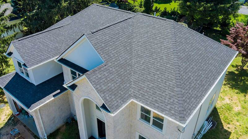Gray shingled roof on a two-story house with white trim, set in a yard.