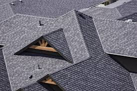 Overhead view of multiple gray shingle roofs with varying angles and shapes; some have wooden beams.