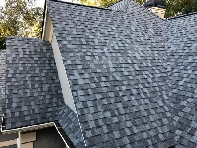 Gray and blue asphalt shingle roof on a house with white trim.