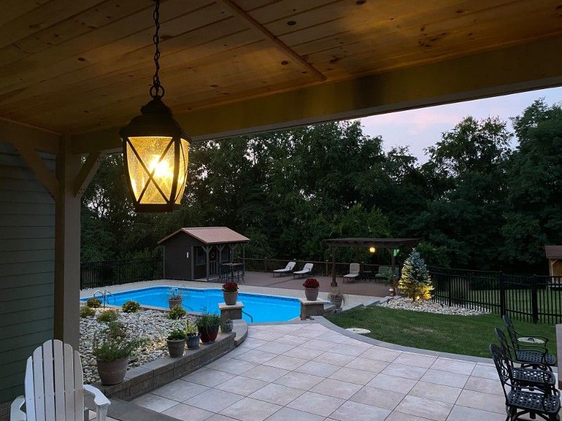 A patio with a pool and a lantern hanging from the ceiling