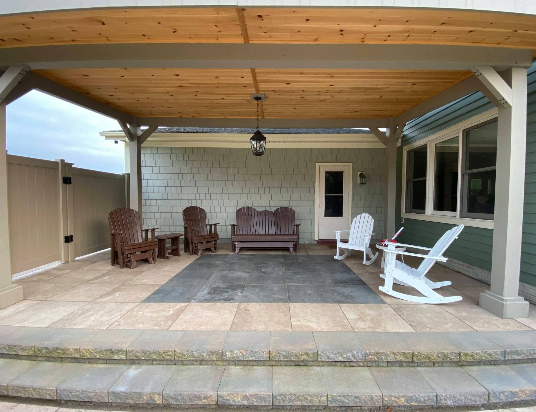A patio with rocking chairs and a couch under a wooden roof.