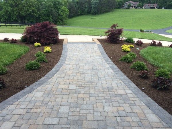 A brick walkway leading to a lush green field