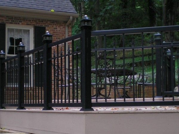 A black fence surrounds a deck with a table and chairs on it.