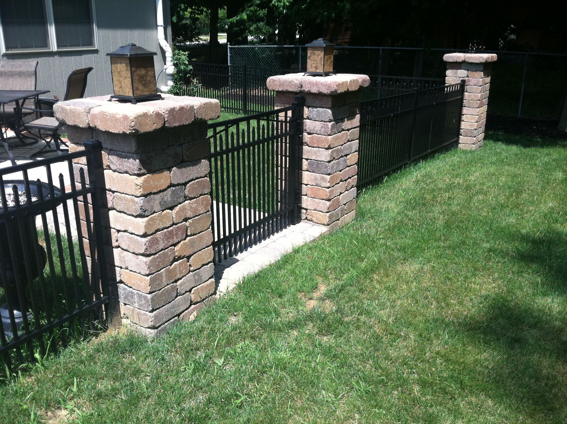 There is a fence with brick pillars and a gate in the backyard.